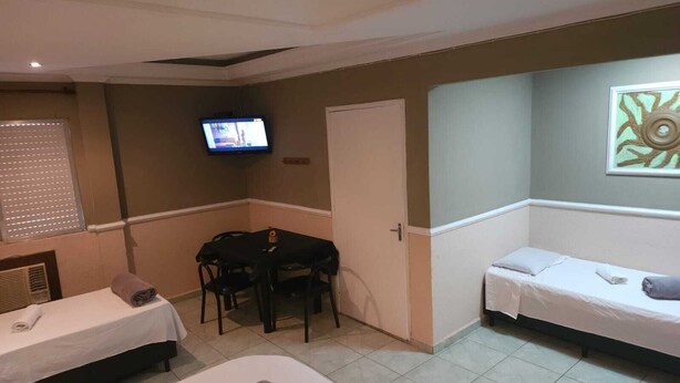 Ein Hotelzimmer mit zwei Betten, einem Schreibtisch, einem Fernseher und einer Tür.