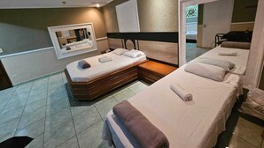 Ein Hotelzimmer mit zwei Betten, einer Sitzecke, einem Spiegel und einem Badezimmer.
