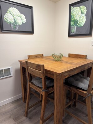 Una mesa de comedor con sillas, un cuenco decorativo y dos cuadros en la pared.