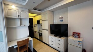 Una cocina compacta con comedor, televisor y refrigerador.