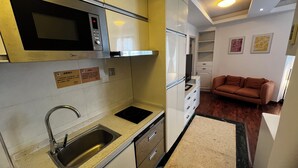 Una cocina compacta con microondas, lavamanos y una pequeña encimera.