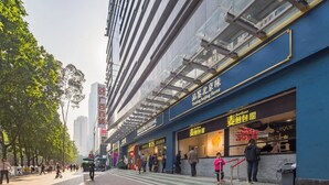 Calle con un edificio que tiene un restaurante llamado 'Tasting Beijing flavor' y un anuncio para 'Guangzhou Daily'.