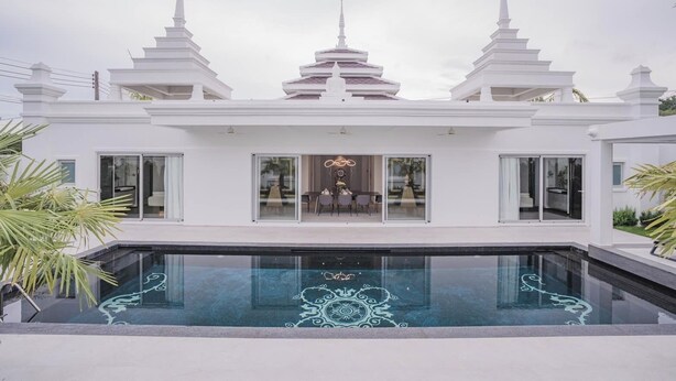 Une maison moderne dotée d’une piscine, de grandes fenêtres et d’un coin repas.