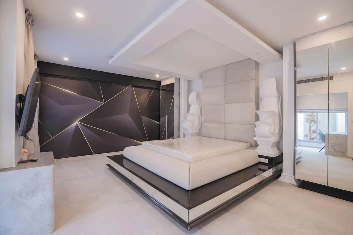 Een moderne slaapkamer met een groot bed, een geometrisch wandontwerp en uitzicht op de omgeving.