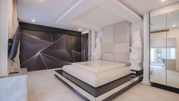 Un dormitorio moderno con una cama grande, un diseño geométrico en la pared y vistas al exterior.
