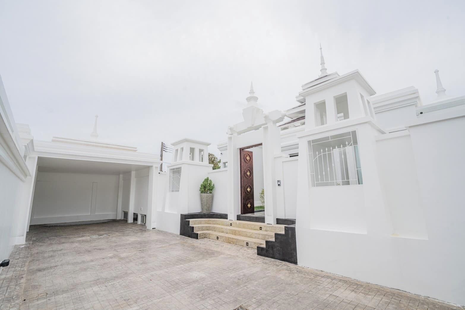 Un edificio blanco con una entrada central, una planta en maceta y una escalera que lleva a la puerta.