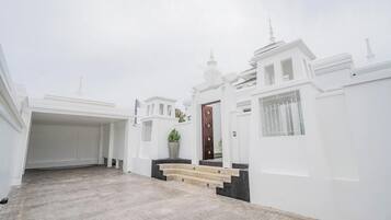 Un edificio blanco con una entrada central, una planta en maceta y una escalera que lleva a la puerta.