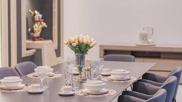 Un comedor moderno con una mesa larga dispuesta para una comida, sillas, un jarrón de flores y una lámpara de techo original.