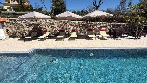 A pool with clear water, surrounded by stone walls and wooden deck.