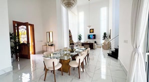 A spacious dining area with a glass table, white chairs, and a chandelier. - Luxury 4-Bedroom Villa | Puerto Plata | Private Pool & Resort (Puerto Plata)