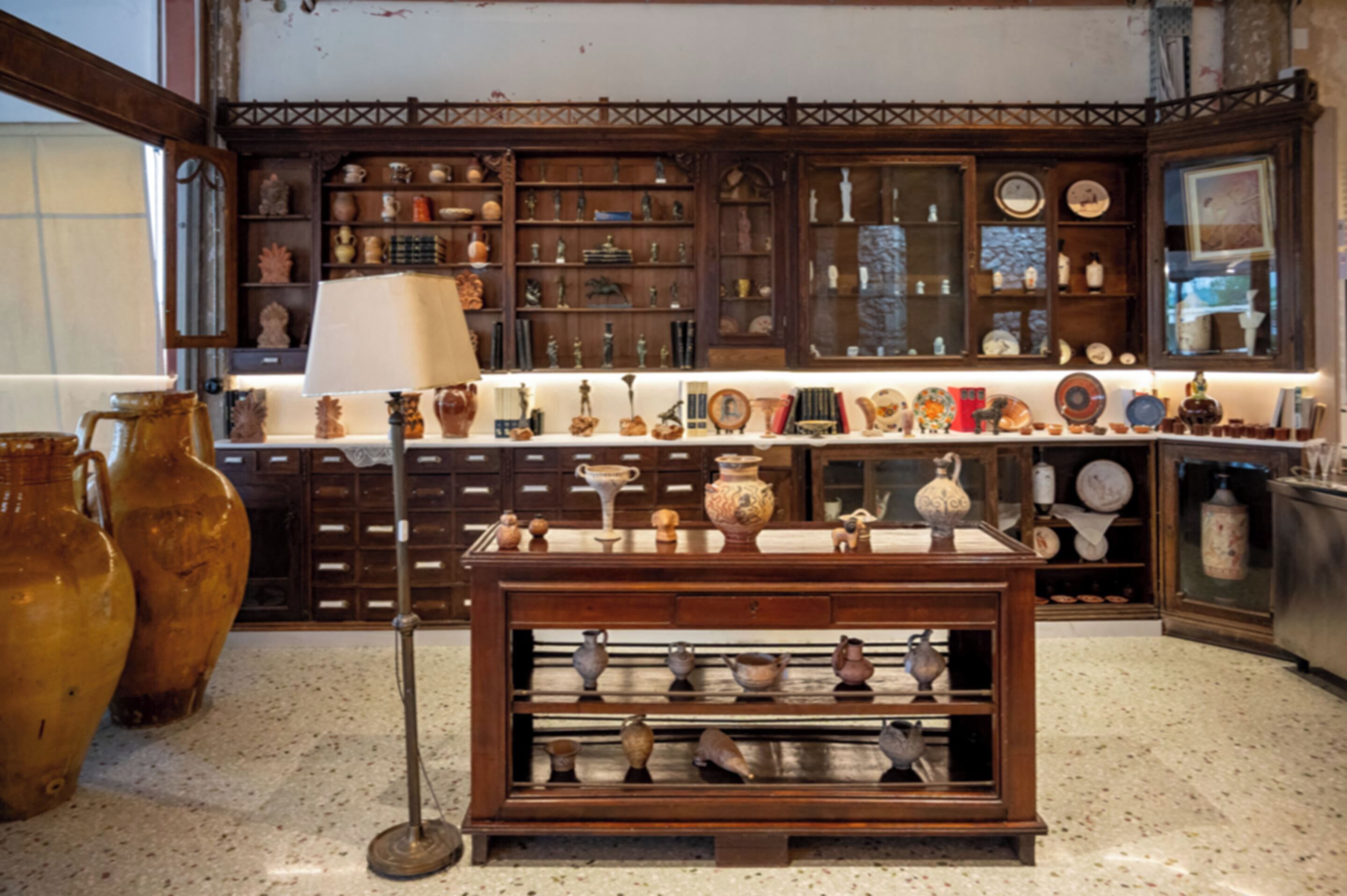 A room with a wooden cabinet filled with various pottery and decorative items.