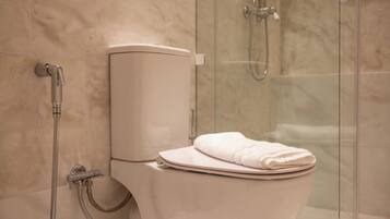Un baño moderno con inodoro, ducha y zona de ducha con paredes de vidrio.