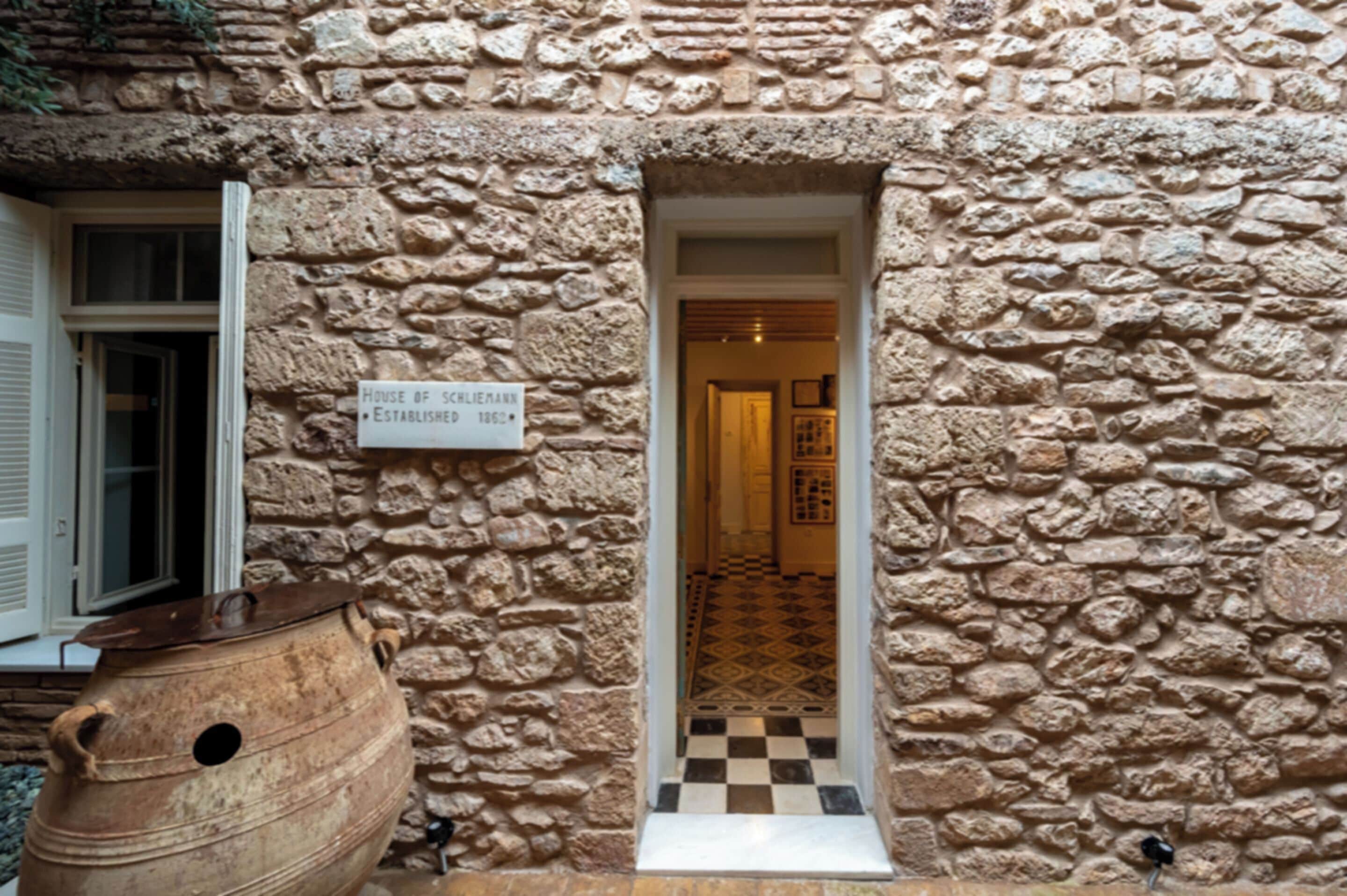 Fachada de piedra con una puerta que da a un pasillo interior con suelo estampado.