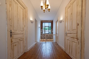 A hallway with wooden doors, a stone wall, and a window with a view. - La Belle Hélène de Ménélas 1862 (Mykines)