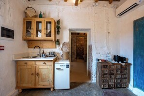 A compact kitchen with wooden cabinets, a small refrigerator, and a blue door. - La Belle Hélène de Ménélas 1862 (Mykines)