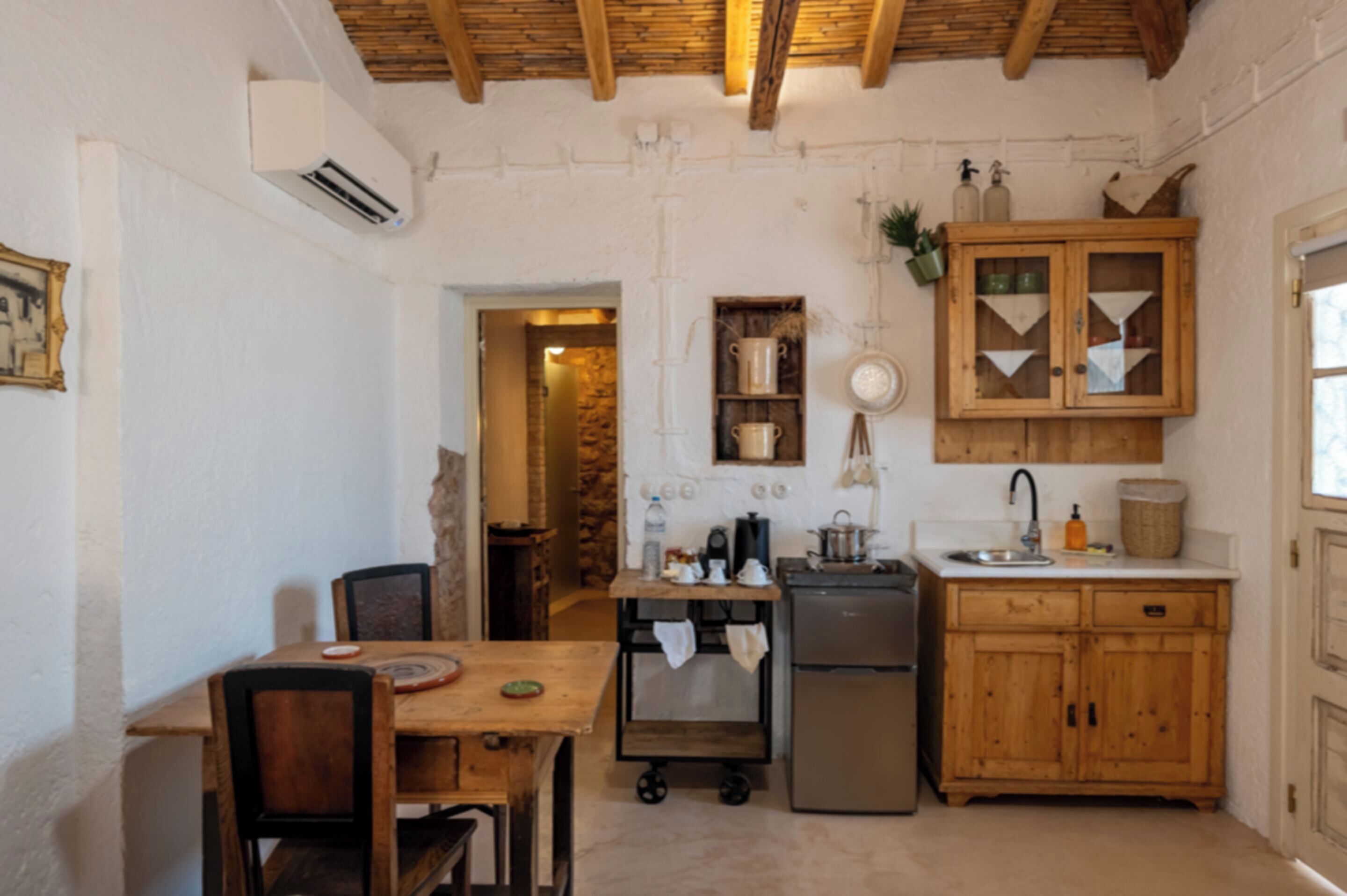 Uma cozinha compacta com armários de madeira, geladeira e área de refeições com mesa e cadeiras.