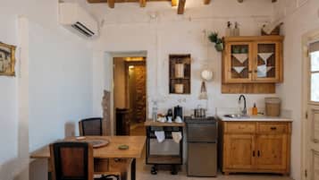 Uma cozinha compacta com armários de madeira, geladeira e área de refeições com mesa e cadeiras.