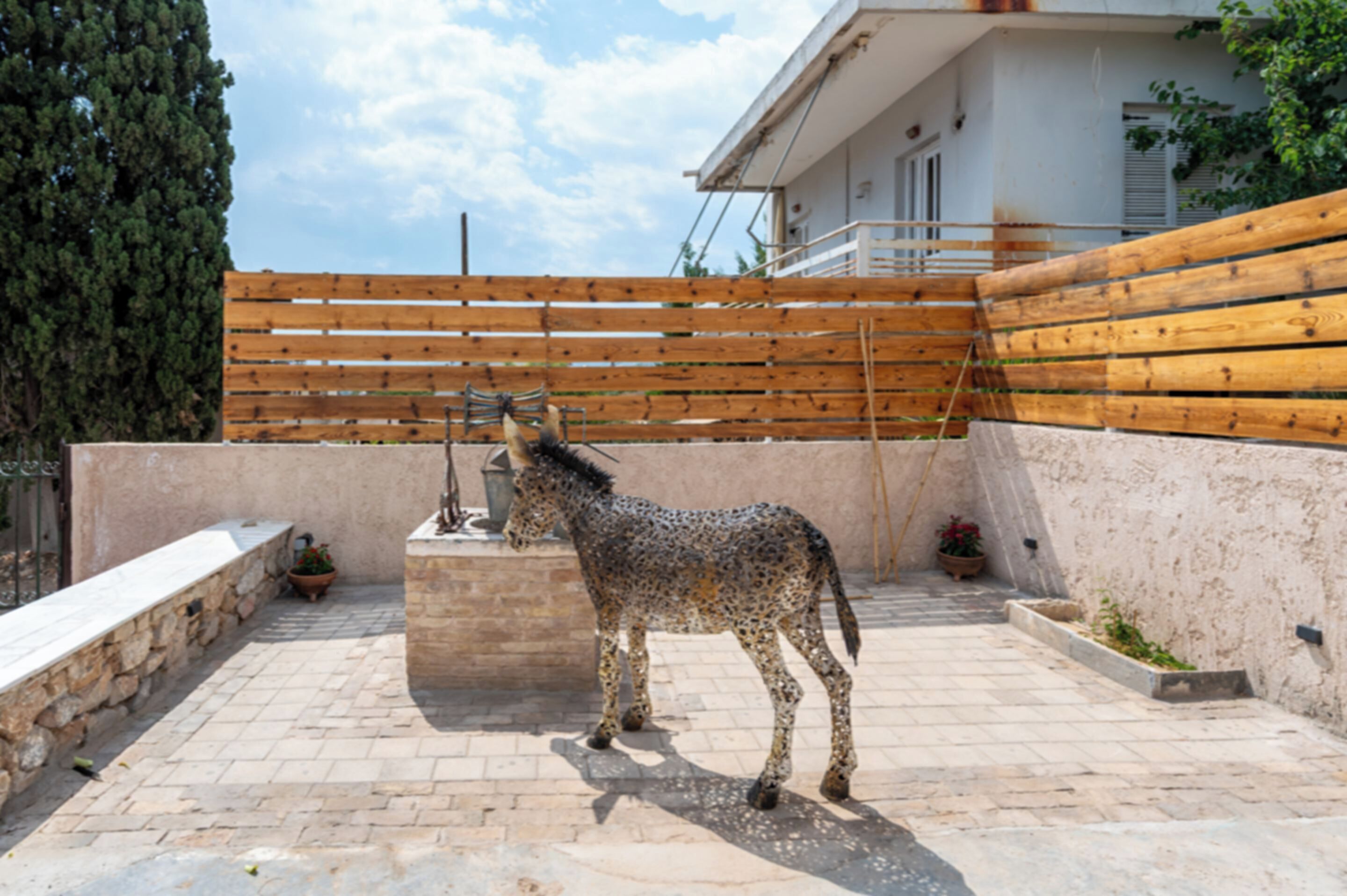 Un patio con una estatua de un caballo, una valla de madera y un edificio con balcón.