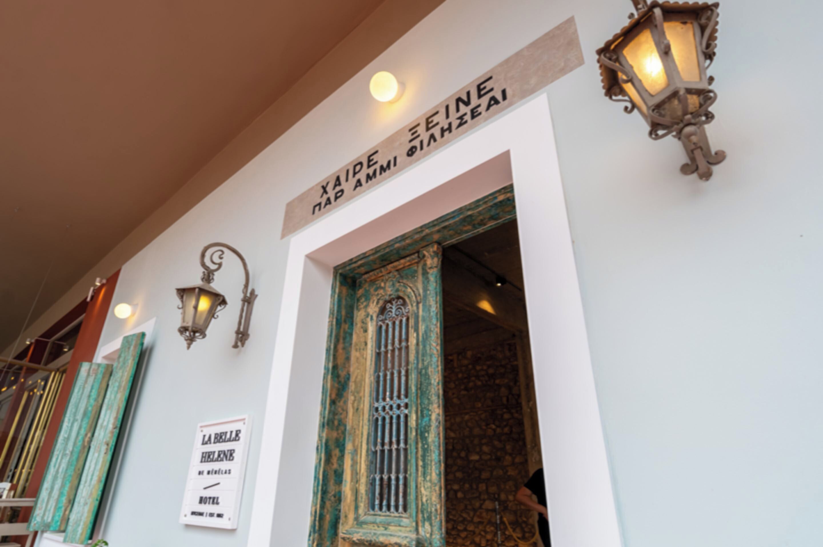 Entrada de hotel con un letrero que dice 'XIAIDE PAI AMI PAIHZEAI' y un letrero que anuncia 'LA BELLE HELENE HOTEL'.