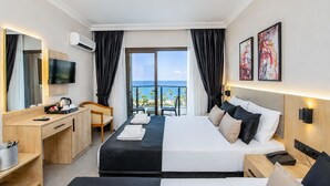 A hotel room with a bed, desk, chair, TV, artwork, and a view of the ocean. - World Star Beach Resort & Spa (Alanya)