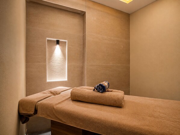 A massage table with towels, a window with natural light, and a wall-mounted light fixture. - World Star Beach Resort & Spa (Alanya)