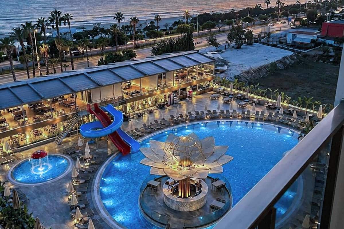 A resort pool area with a water slide, multiple pools, and lounge chairs.