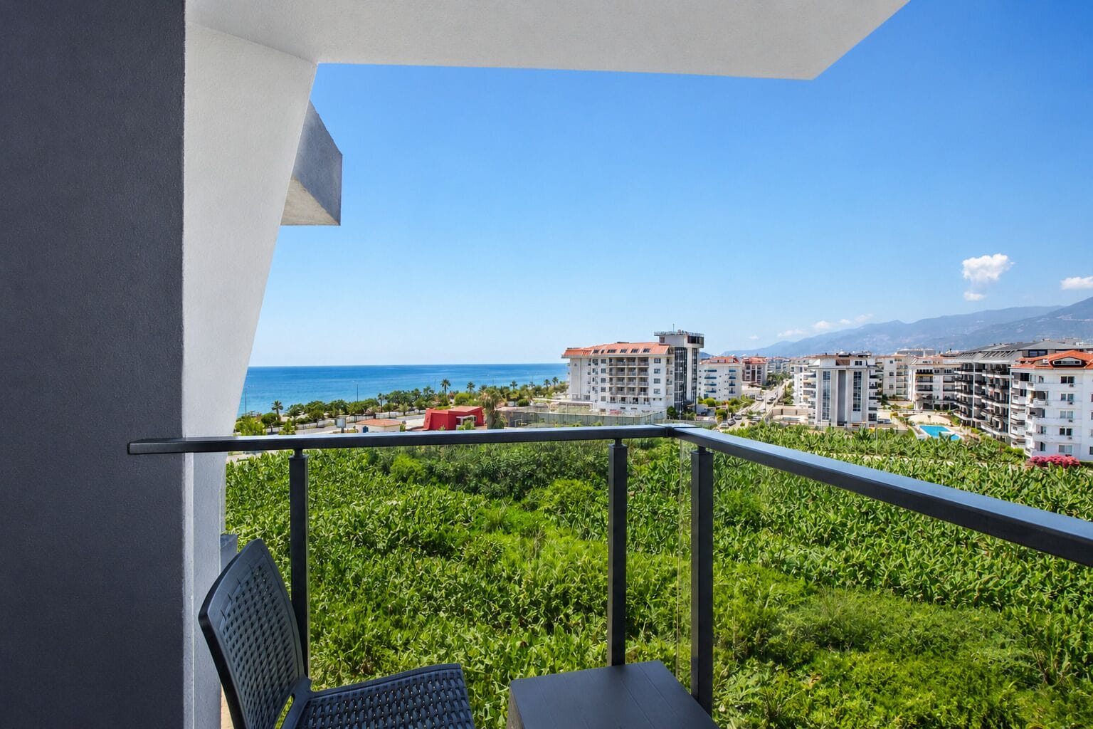Un balcon avec vue sur la mer, les bâtiments et la verdure.