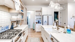A modern kitchen with white cabinetry, a stainless steel range, a marble countertop, and a built-in oven. - Luxury Pistache Park Retreat | Private Pool + Hot Tub | Carlton Landing (Carlton Landing)