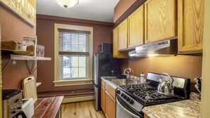 Una cocina compacta con armarios de madera, estufa, refrigerador y ventana.