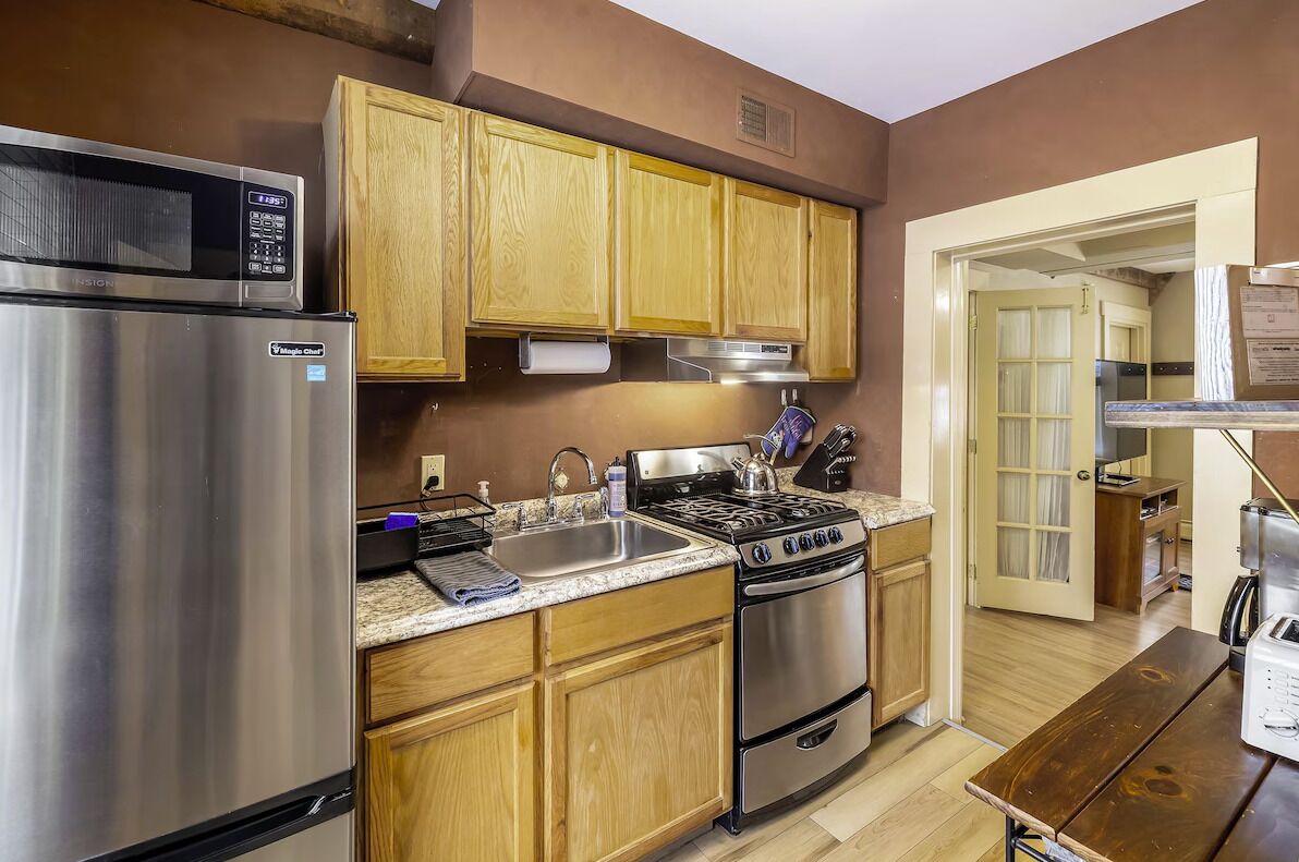 A kitchen with wooden cabinets, a stainless steel refrigerator, a stove, and a sink.
