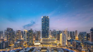 A cityscape with a prominent skyscraper, marina with boats, and surrounding high-rise buildings. - LUX  The Aurora Marina View Suite (Dubai)