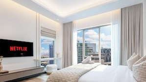 A modern hotel room with a large window, a flat-screen TV, a bed, and a small seating area. - LUX  The Aurora Marina View Suite (Dubai)