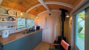 A kitchen with wooden ceiling, a stove, and a window with a view.