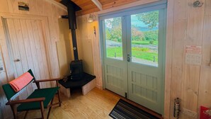 A wooden interior with a fireplace, a door leading outside, and a chair.