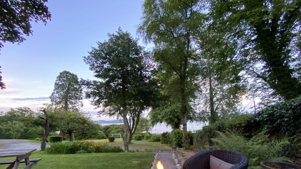 A patio with a fire pit, wicker furniture, and a view of the landscape.