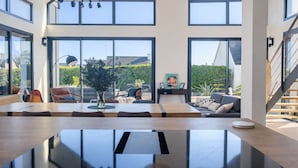 A spacious room with a large dining table, a sofa, and a staircase. - Architect-designed villa near the beach Trévignon -South Brittany -France (Trégunc)
