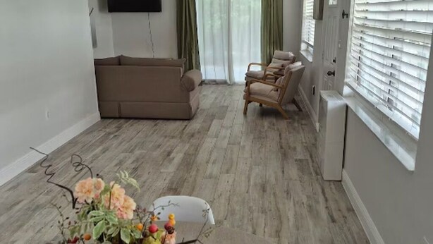 A living room with a sofa, chairs, a TV, and a window with blinds. - Baby Blue! (Port Charlotte)
