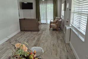 A living room with a sofa, chairs, a TV, and a window with blinds. - Baby Blue! (Port Charlotte)