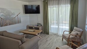 A living room with a sofa, armchairs, a coffee table, a flat-screen TV, and a large window with curtains. - Baby Blue! (Port Charlotte)