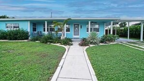 A single-story building with a flat roof, a front porch, and a pathway leading to the entrance. - Baby Blue! (Port Charlotte)