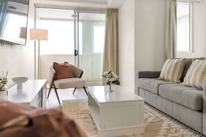 Una sala de estar moderna con un sofá, una mesa de centro, una silla y un televisor montado en la pared.