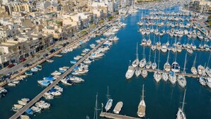 Un puerto deportivo con numerosas embarcaciones amarradas, rodeado de edificios urbanos.