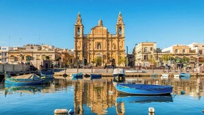 Un edificio histórico con dos torres, un muelle y varios barcos.