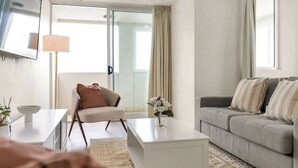 Una sala de estar moderna con un sofá, una mesa de centro, una silla y un televisor montado en la pared.