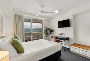 Ein Hotelzimmer mit Bett, Schreibtisch, Stuhl, Fernseher und einem Balkon mit Blick.