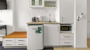 A compact kitchenette with a refrigerator, microwave, sink, and cabinets. - Explore Cairns Esplanade from your Private Studio (Cairns)