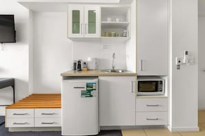 Eine kompakte Küchenzeile mit Kühlschrank, Mikrowelle, Spüle und Schränken.