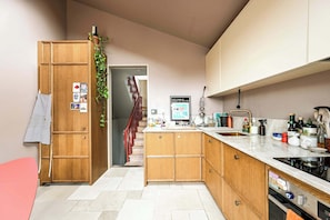 A kitchen with wooden cabinets, a marble countertop, a stainless steel sink, and a stove. - The Sun Deck Townhouse (Greater London)