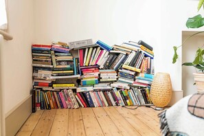 A corner with a stack of books against a wall and a floor lamp. - The Sun Deck Townhouse (Greater London)