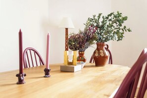 A wooden dining table with a lamp, candles, a vase with plants, and a decorative box. - The Sun Deck Townhouse (Greater London)